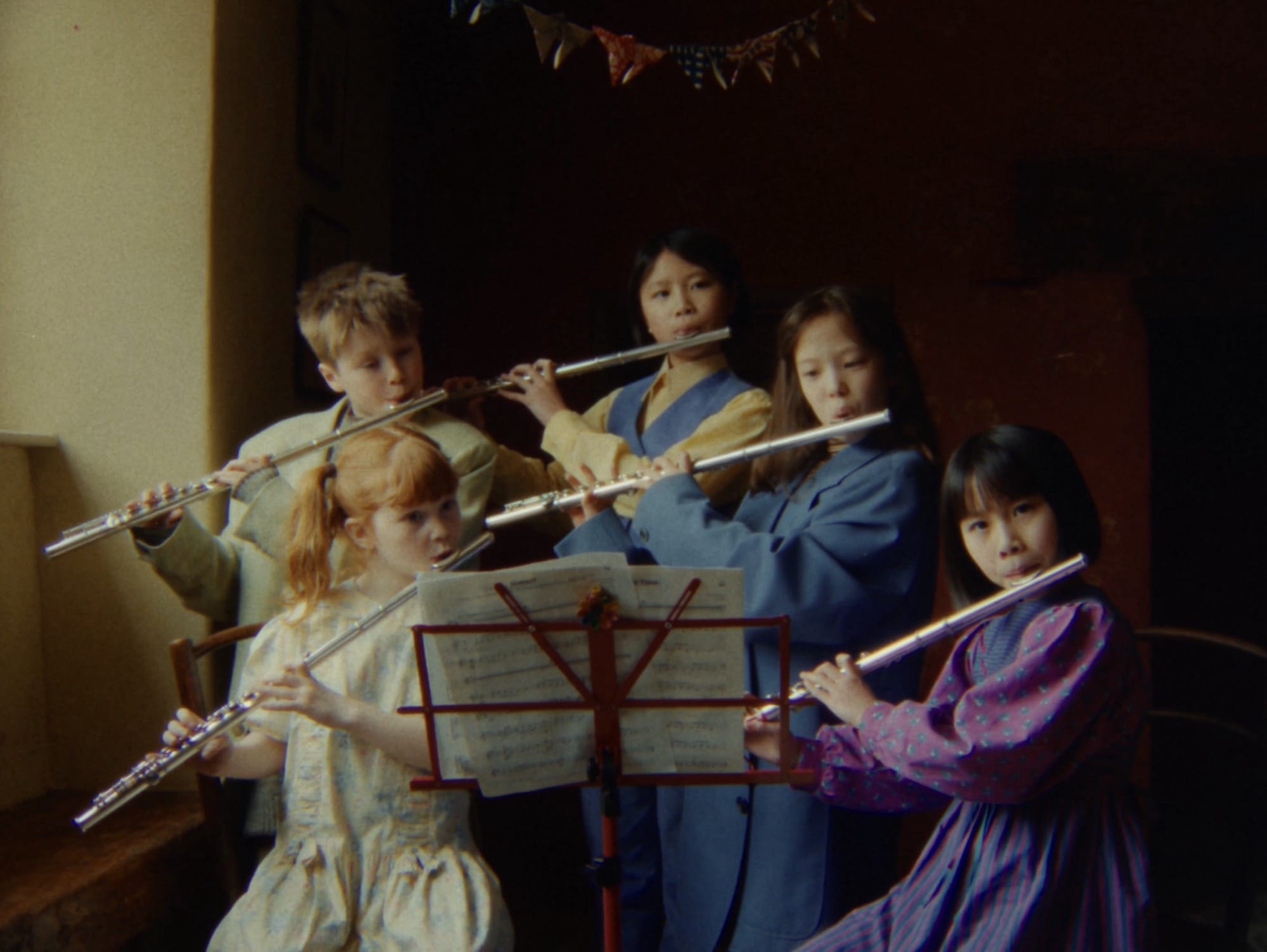 a still from a video titled "A Ffern Fairytail" featuring children playing the flute